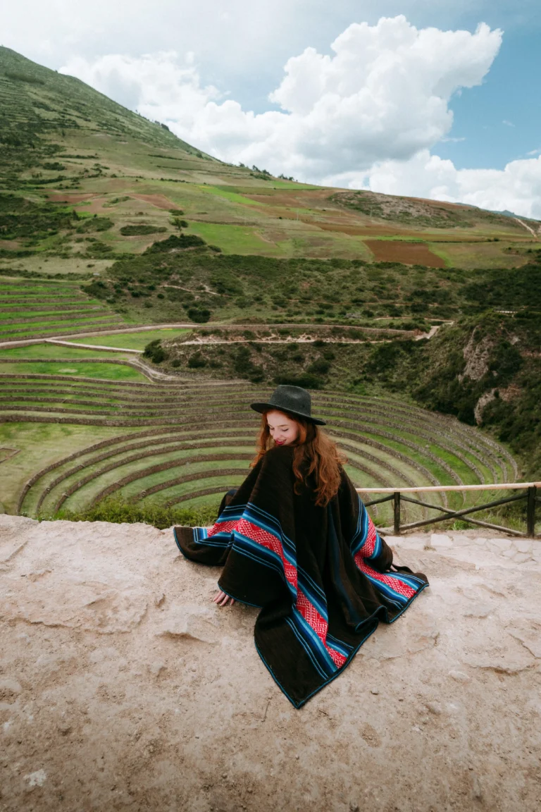 Woman in traditional poncho posing at Moray site